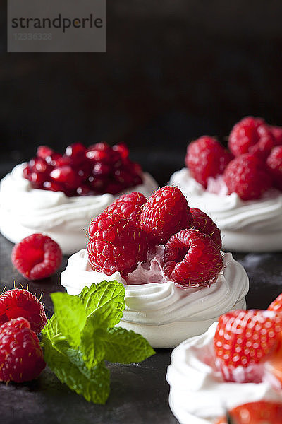 Meringue pastries garnished with whipped cream and raspberries