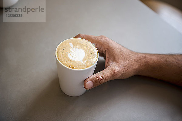 Hand and cup of cappuccino in a cafe