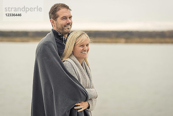 Happy couple standing at lake shore  embracing