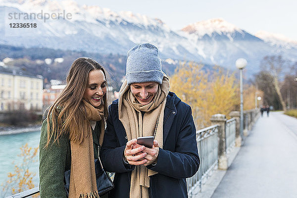Austria  Innsbruck  happy young couple looking at cell phone