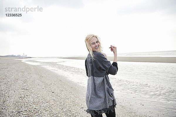 Netherlands  portrait of happy blond young woman on the beach