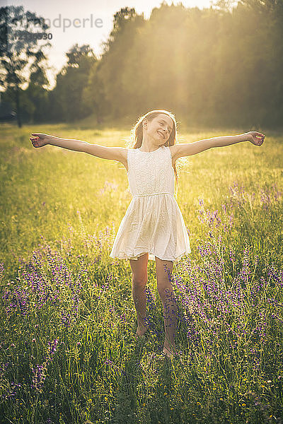 Happy girl dancing on flower meadow at evening twilight