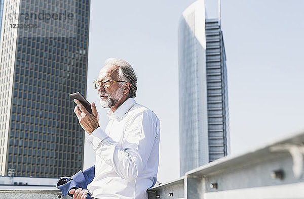 Mature businessman in the city using cell phone