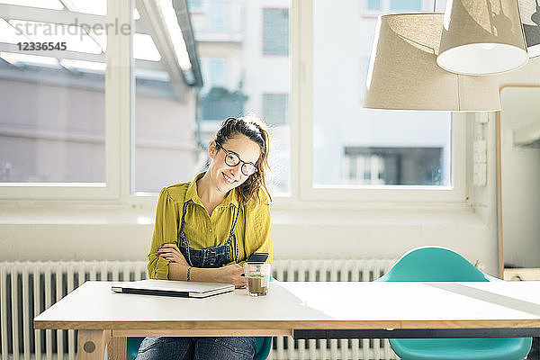 Smiling freelancer sitting at desk in her studio