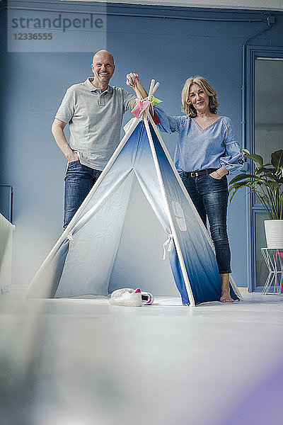 Smiling couple standing at teepee indoors