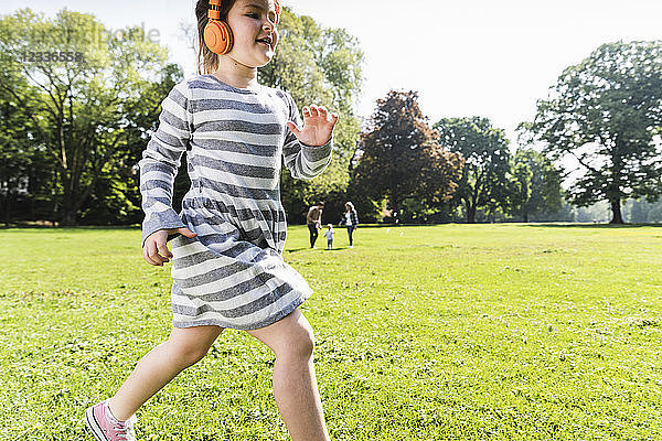 Girl with family in background wearing headphones in a park