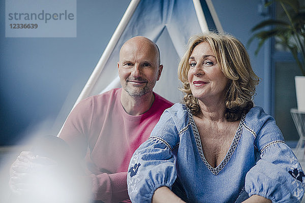 Portrait of smiling couple at teepee indoors