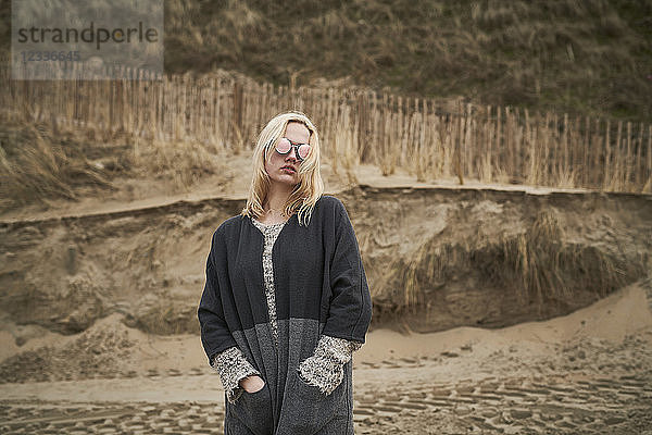 Fashionable blond young woman wearing mirrored sunglasses on the beach