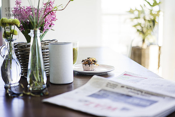 Newspaper  flower vases  loudspeaker and muffin on table