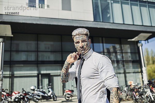 Young businessman with tattooed face walking in the city  portrait