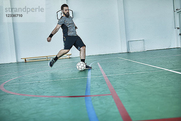 Man playing indoor soccer shooting the ball