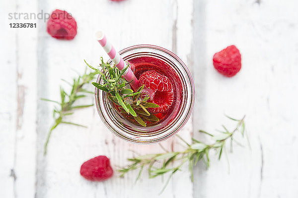 Glass bottle of homemade raspberry lemonade flavoured with rosemary