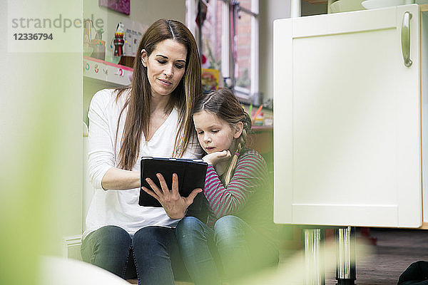 Mother and daughter using tablet together at home