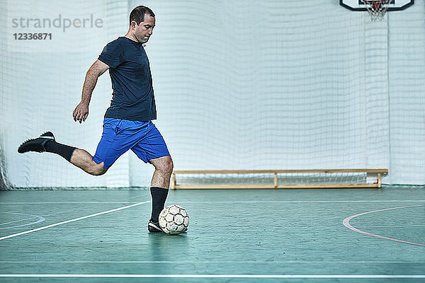 Man playing indoor soccer shooting the ball