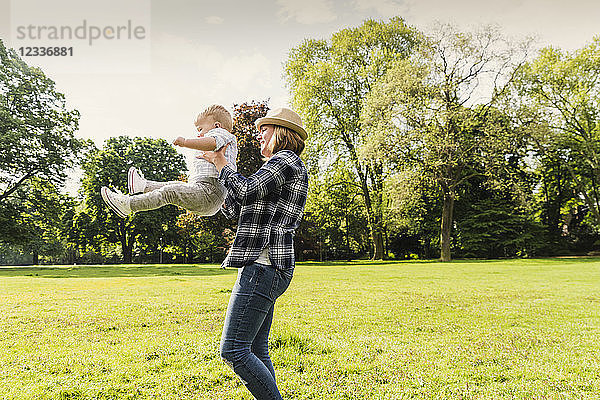 Happy mother lifting up son in a park