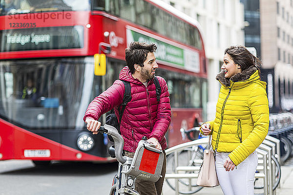 UK  London  young man with rental bicycle from bike share stand talking to his girlfriend