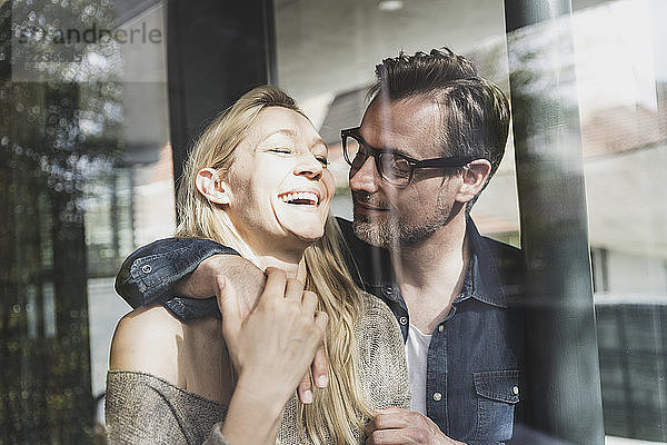 Happy mature couple behind windowpane at home