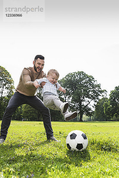 Happy father playing football with son in a park