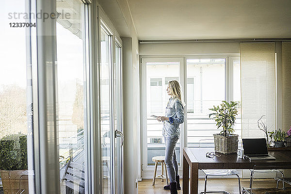 Woman with tablet looking out of window