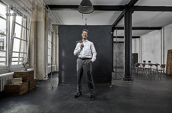 Portrait of mature businessman in front of black backdrop in loft