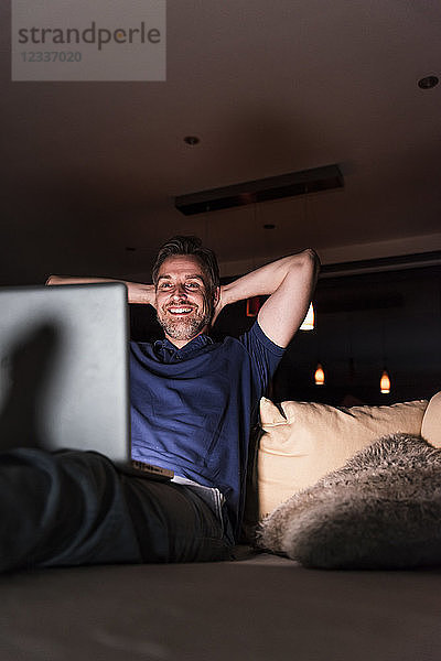 Man sitting on couch at home looking at laptop