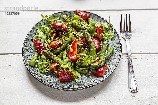 Salad of green asparagus  rocket  strawberries and pine nuts