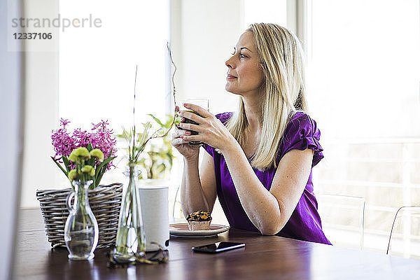 Mature woman sitting at table relaxing with glass of coffee