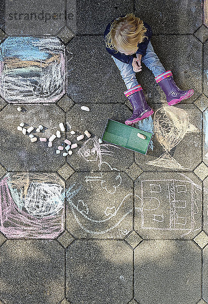 Little girl after drawing with chalk outdoors  top view