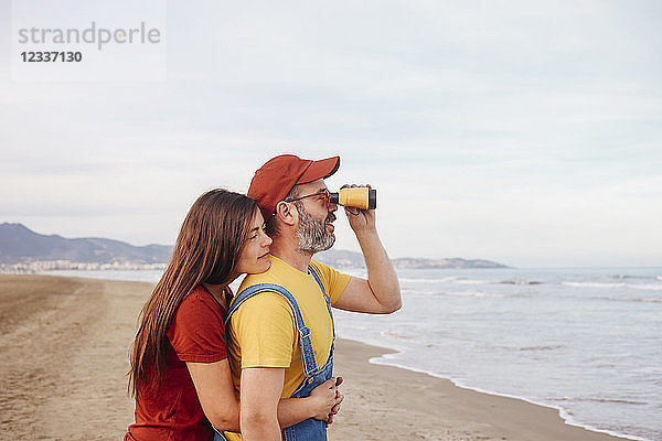 Couple with binoculars on the beach