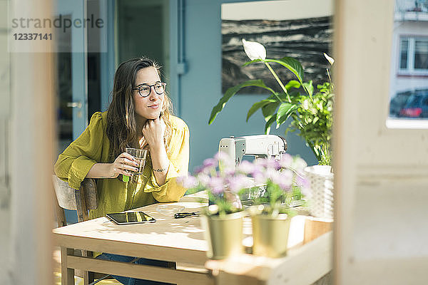 Portrait of smiling fashion designer sitting at desk in her studio