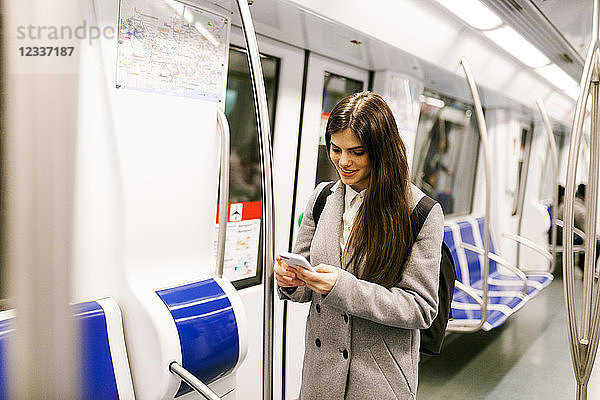 Spain  Barcelona  young woman in underground train looking at cell phone