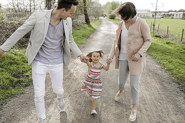 Little girl holding hands of parents while running