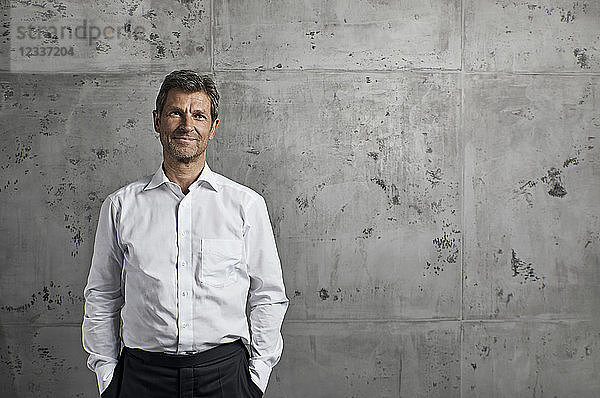 Portrait of smiling mature man in front of concrete wall