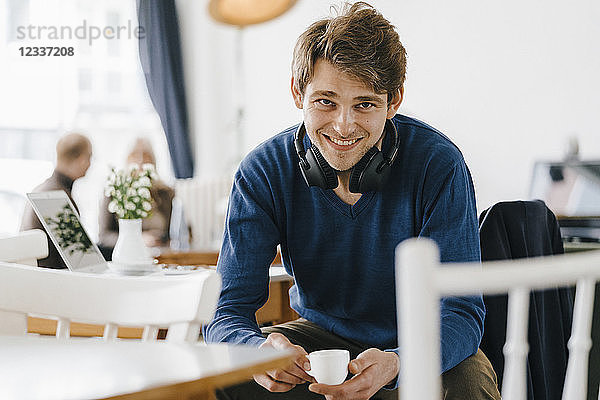 Portrait of smiling man in a cafe wearing headphones