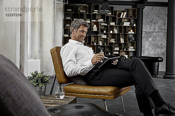 Mature man using digital tablet with digital pen in loft