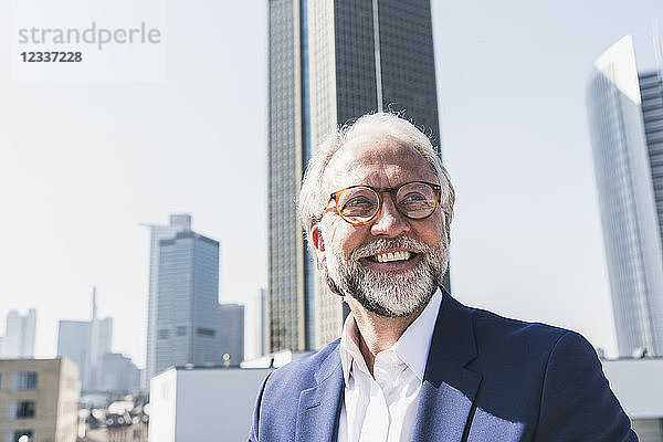 Portrait of happy mature businessman in the city looking around