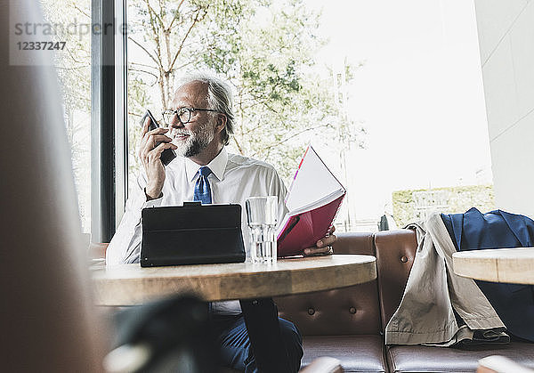 Smiling mature businessman working at table in a cafe