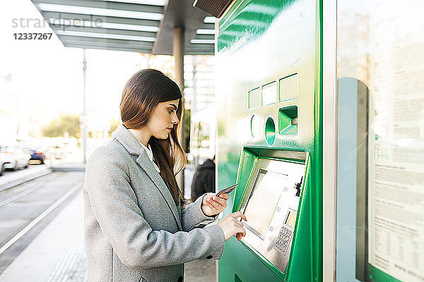 Spain  Barcelona  woman buying ticket from automated machine at station