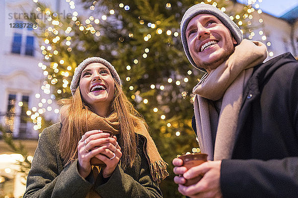 Laughing young couple drinking mulled wine at Christmas market