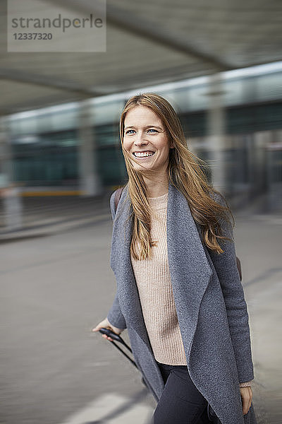 Portrait of confident businesswoman pulling suitcase at airport