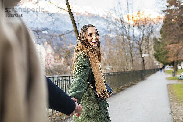 Austria  Innsbruck  portrait of happy young woman strolling hand in hand with her boyfriend at winter time