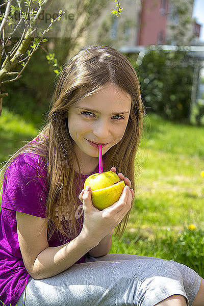 Portrait of smiling girl drinking Strawberry Smoothie in garden