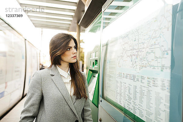 Spain  Barcelona  portrait of young businesswoman looking at map at station