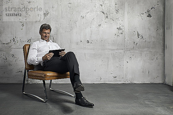 Mature man using digital tablet in front of concrete wall