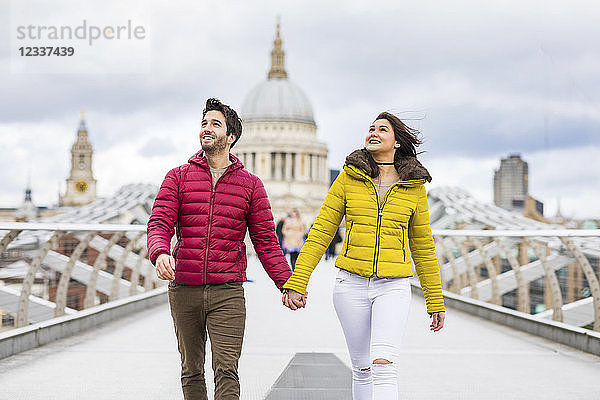 UK  London  young couple walking hand in hand on bridge in front of St Pauls Cathedral