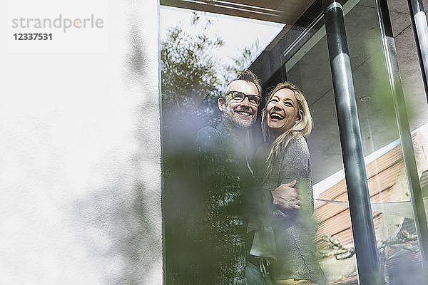 Happy mature couple standing on terrace of their house