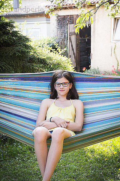 Portrait of smiling girl sitting on a hammock in the garden