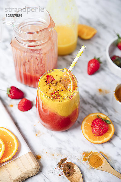 Strawberry and orange smoothie with curcuma and cinnamon on marble