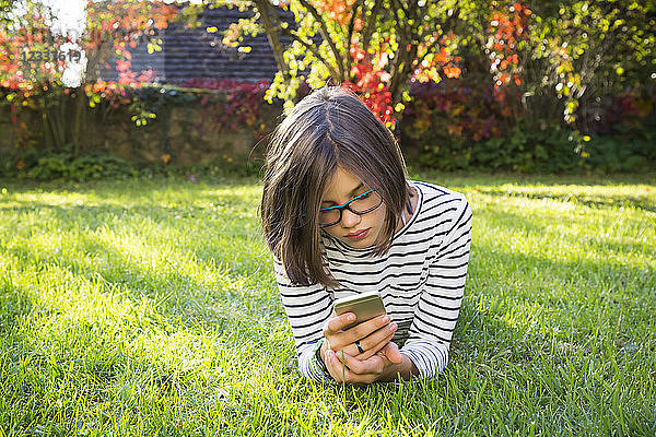 Girl lying on meadow using smartphone