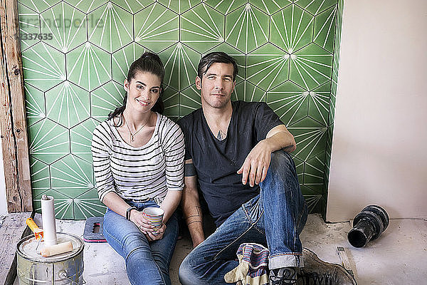 Couple renovating new house  sitting on ground taking a break